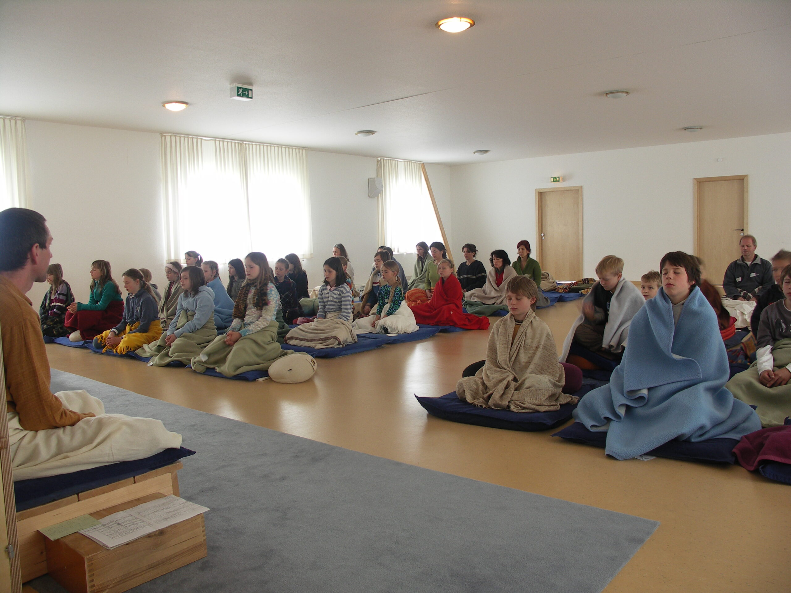 Children meditate together with an assistant teacher in the meditation hall